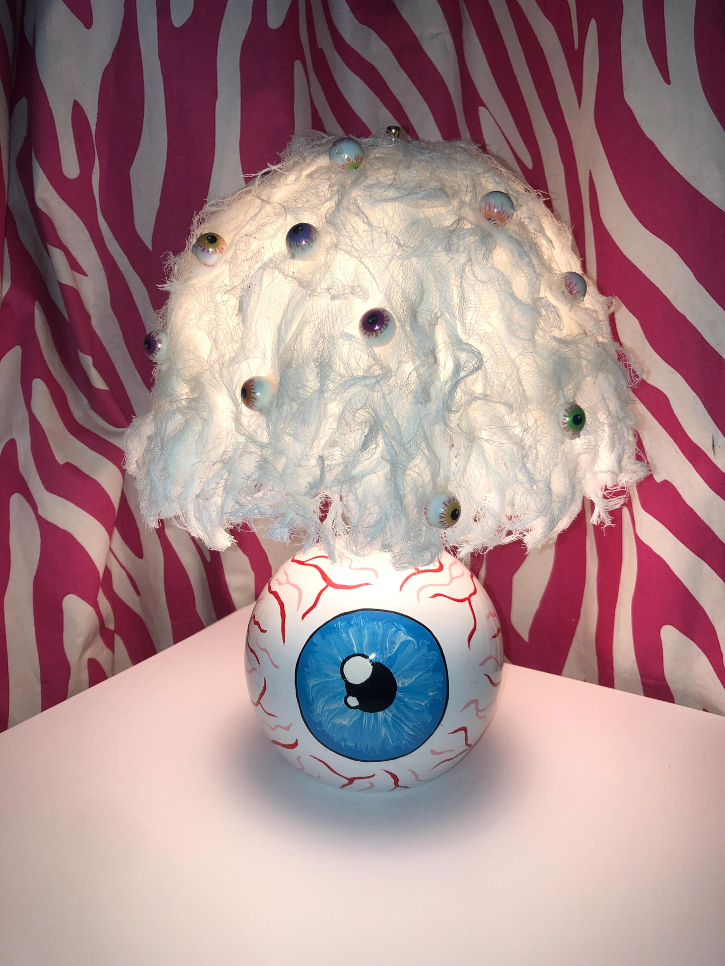 Eyeball lamp with a hand-painted base and a shade covered in doll eyes